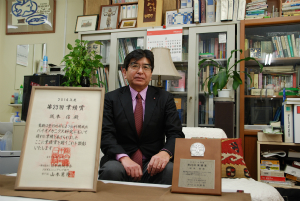 賞状と盾と坂本信教授(医学部保健学科)