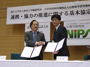 協定書を手に固い握手を交わす両所長