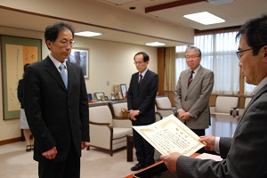 髙橋学長(右)から賞状を手渡される俣野教授(左)