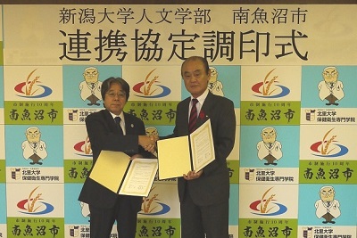 握手を交わす高木人文学部長(左)と井口南魚沼市長