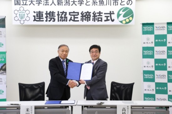 協定書に署名し，握手する米田糸魚川市長（左）と髙橋学長（右）