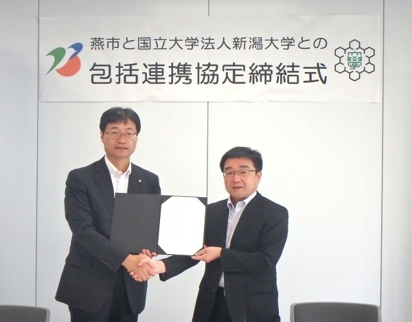 握手を交わす鈴木燕市長(左)と髙橋学長(右)
