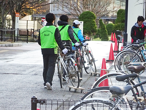 早朝の寒空の下，放置自転車を整理する学生達