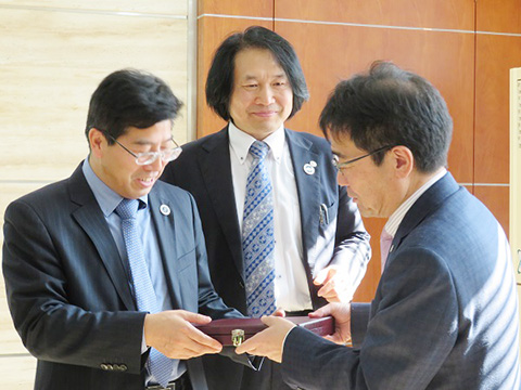 記念品を贈呈する髙橋学長と立ち合われた李教授（中央）