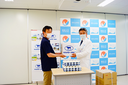 有限会社ヤスダヨーグルトからヨーグルトの無償提供を受け取る冨田 善彦医歯学総合病院長