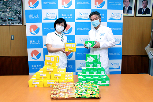 お菓子を受け取る病院スタッフと冨田善彦新潟大学医歯学総合病院長