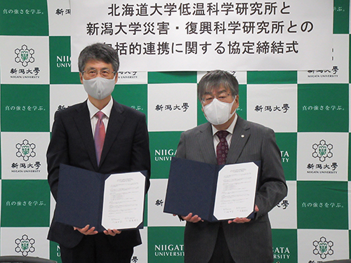 協定書を掲げる北海道大学低温科学研究所長（左）と本学災害・復興科学研究所長（右）