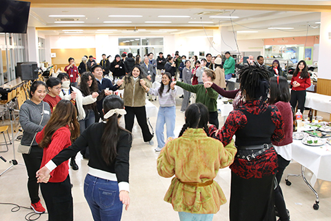 手を取り合い、輪になって踊る留学生や日本人学生たち