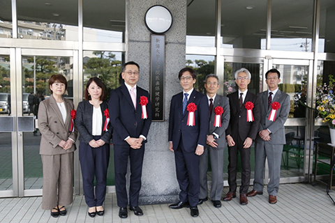 銘板を囲んで集合写真